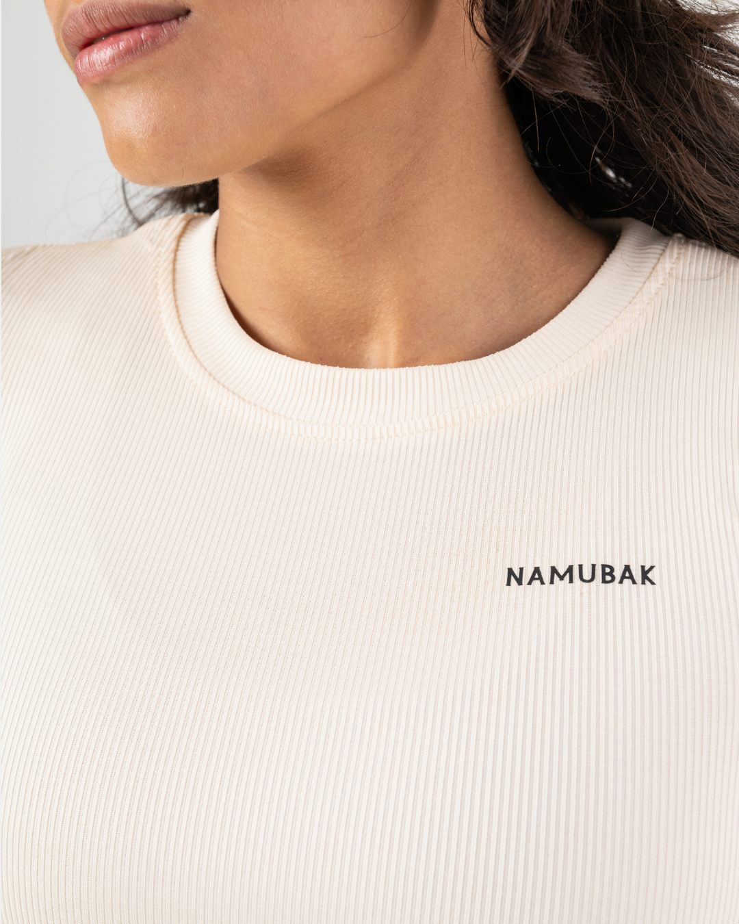 Foto de cerca de una mujer utilizando un croptop crema reciclado Namubak. Un cropto ideal para explorar