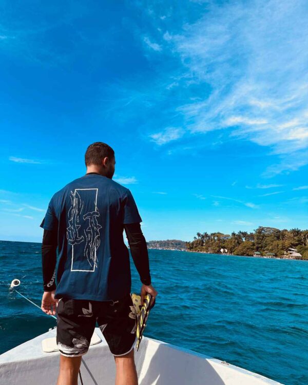 Foto de un hombre viendo el oceano en un barco y utilizando una camisa de Un Tiburon Martillo