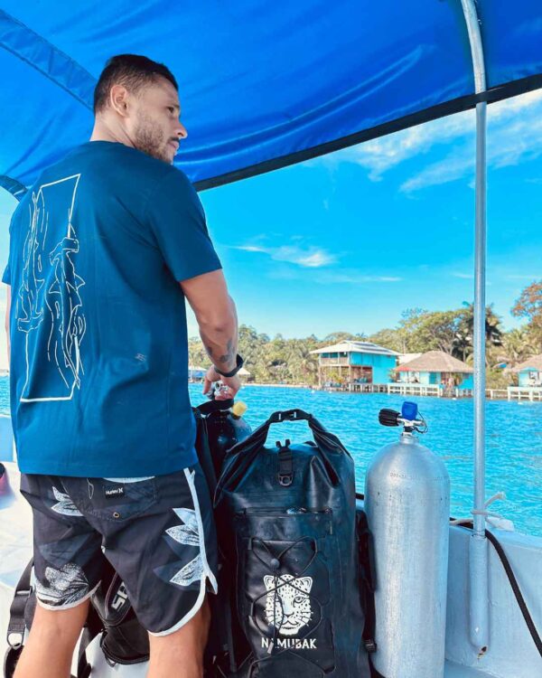 Foto de un hombre viendo el oceano en un barco y utilizando una camisa de Un Tiburon Martillo