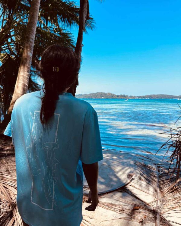 Foto de una mujer viendo el oceano y utilizando una camisa de Un Tiburon Martillo